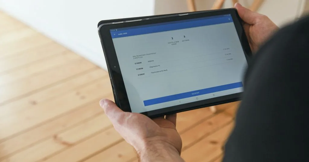 Mann hält Tablet mit Web-App in Händen.