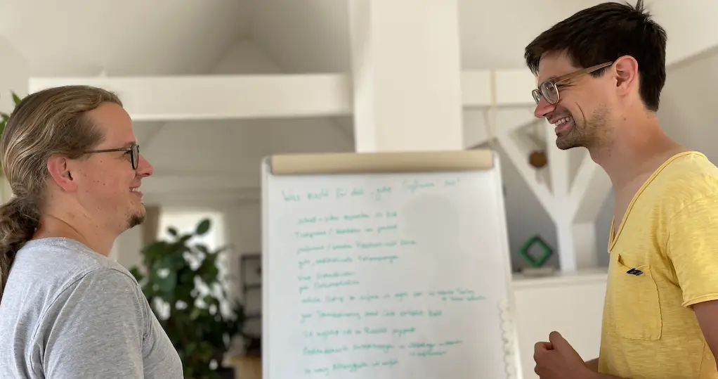 Dominik Burgdörfer und Jonas Meer im Gespräch vor einem Flipchart mit Notizen.