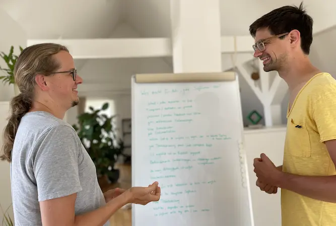 Dominik Burgdörfer und Jonas Meer im Gespräch vor einem Flipchart mit Notizen.