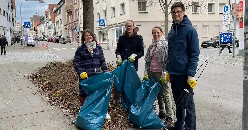 Mareike und Dominik Burgdörfer, Franziska Riesenberg und Jonas Meer stehen lächelnd, mit Müllsäcken und Greifzangen, vor einem Baum.