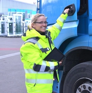 Truck driver standing with her tablet in front of her truck.